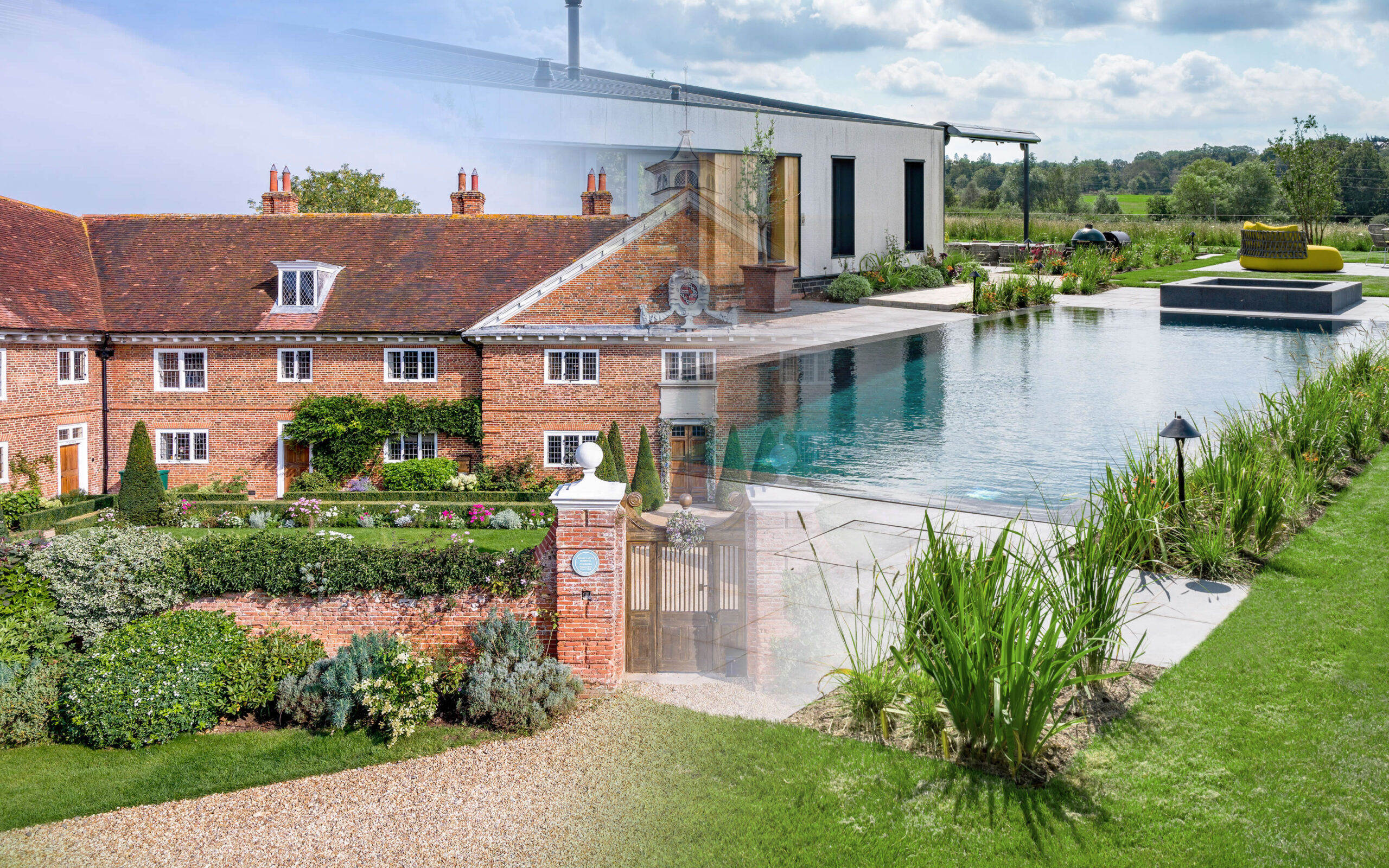 Luxurious garden scene with a brick house, a modern white wing, and a rectangular reflecting pool amid landscaped greenery.